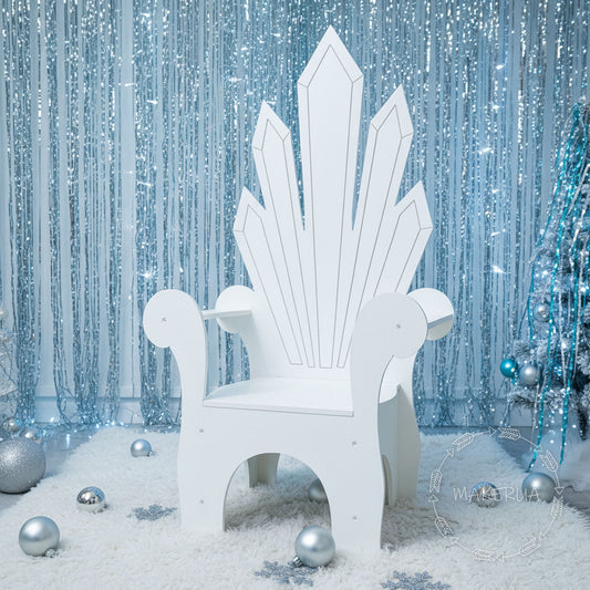 White wooden princess throne chair with ice crystal backrest design, set in a winter wonderland scene with silver decor. Birthday party photo prop.