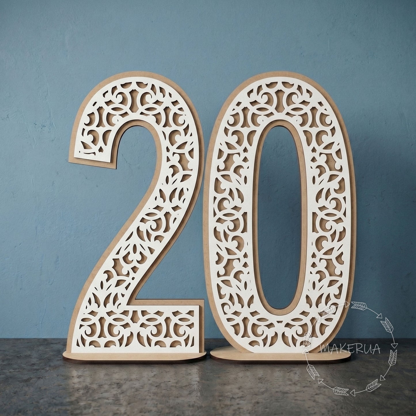 Two-layered freestanding white laminated HDF numbers 20 with intricate laser-cut lace and filigree pattern on a wooden stand against a blue studio background.